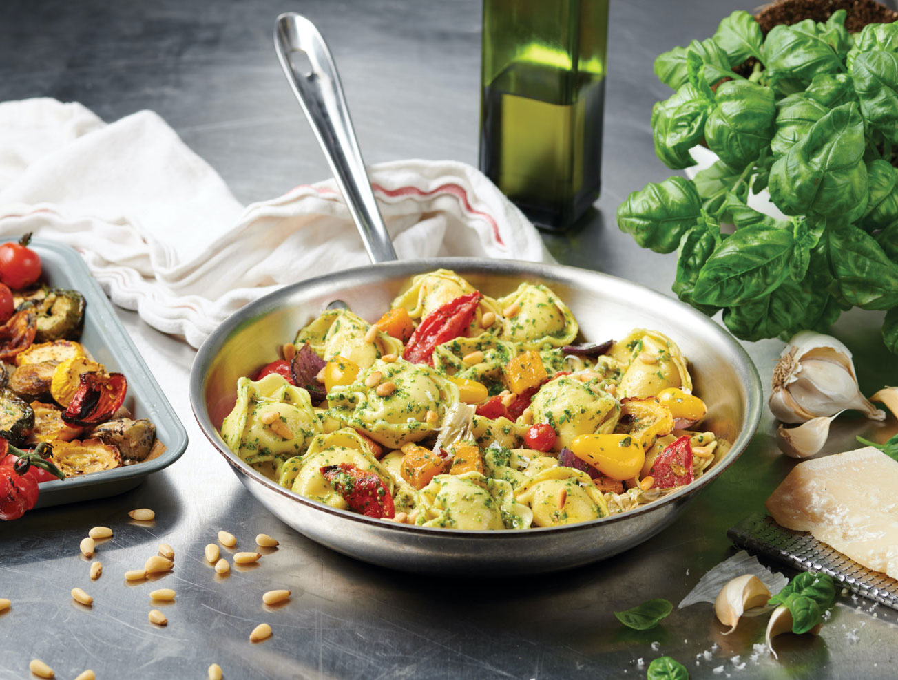 A sauté pan with Tortelloni, pesto, tomatoes and pine nuts