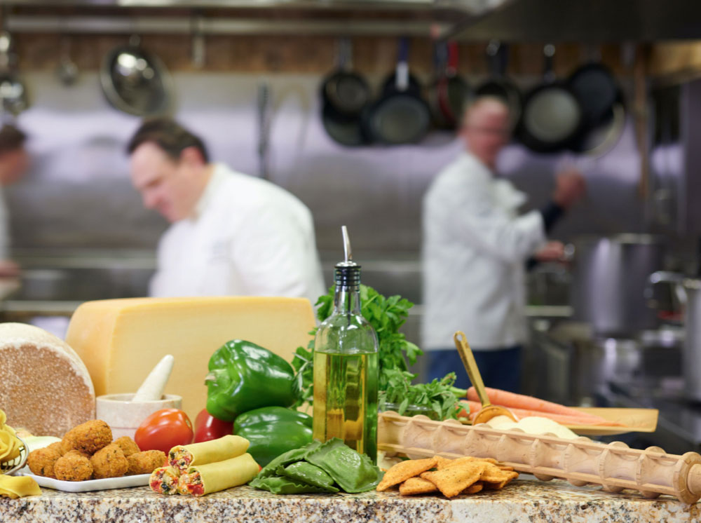 Ingredients displayed on a table with chefs cooking in the background