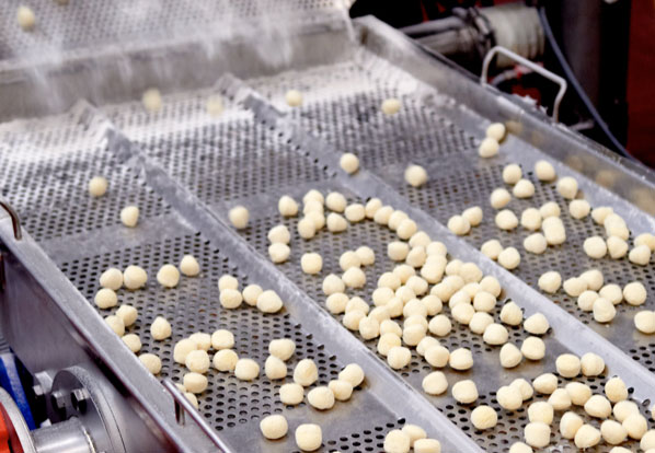 Gnocchi being rolled on a factory machine