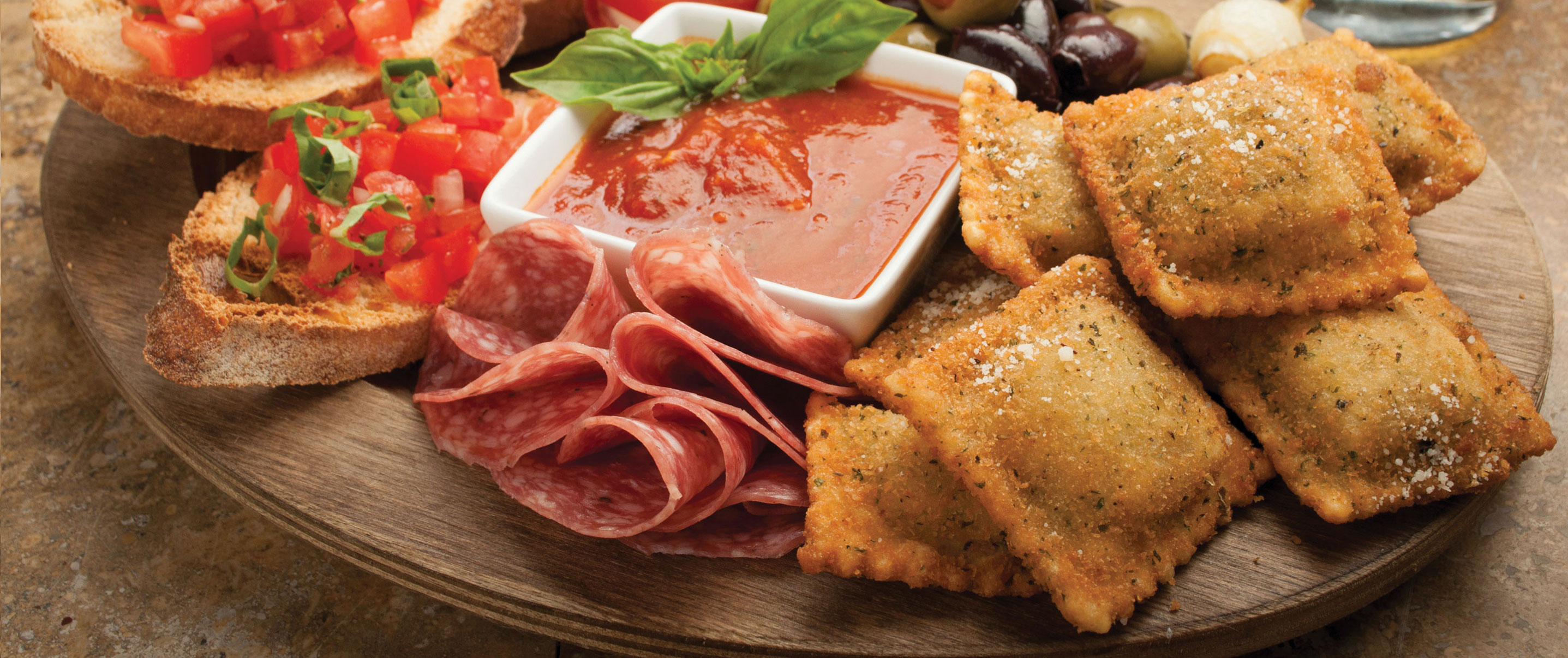 Breaded Ravioli on a platter with salami, bruschetta and olives 